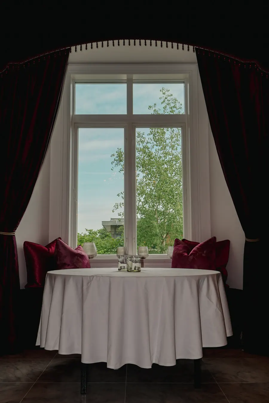 A table laid by the window with red curtains